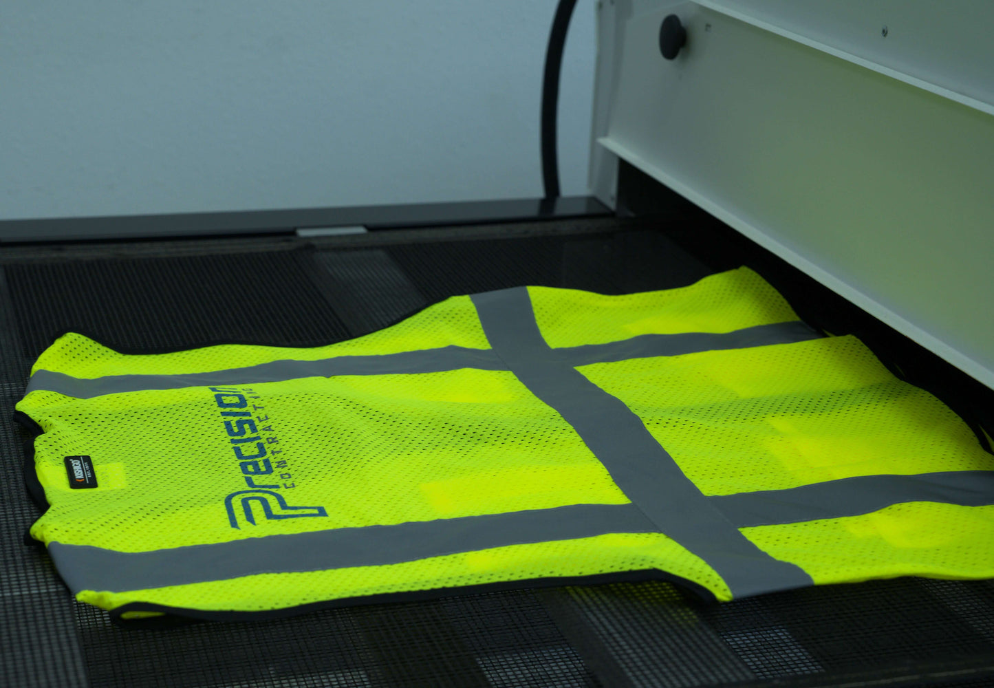 Yellow safety vest being screen printed in the back for precision contracting, a general contractor.
