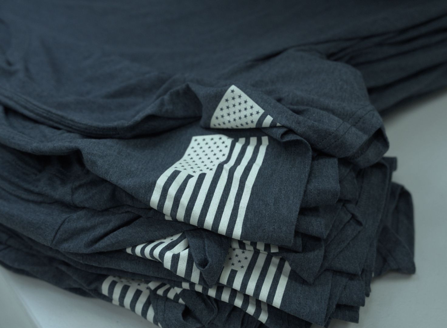 Screen printed shirt with the flag of the united states of america in one of its sleeves layed down on a table