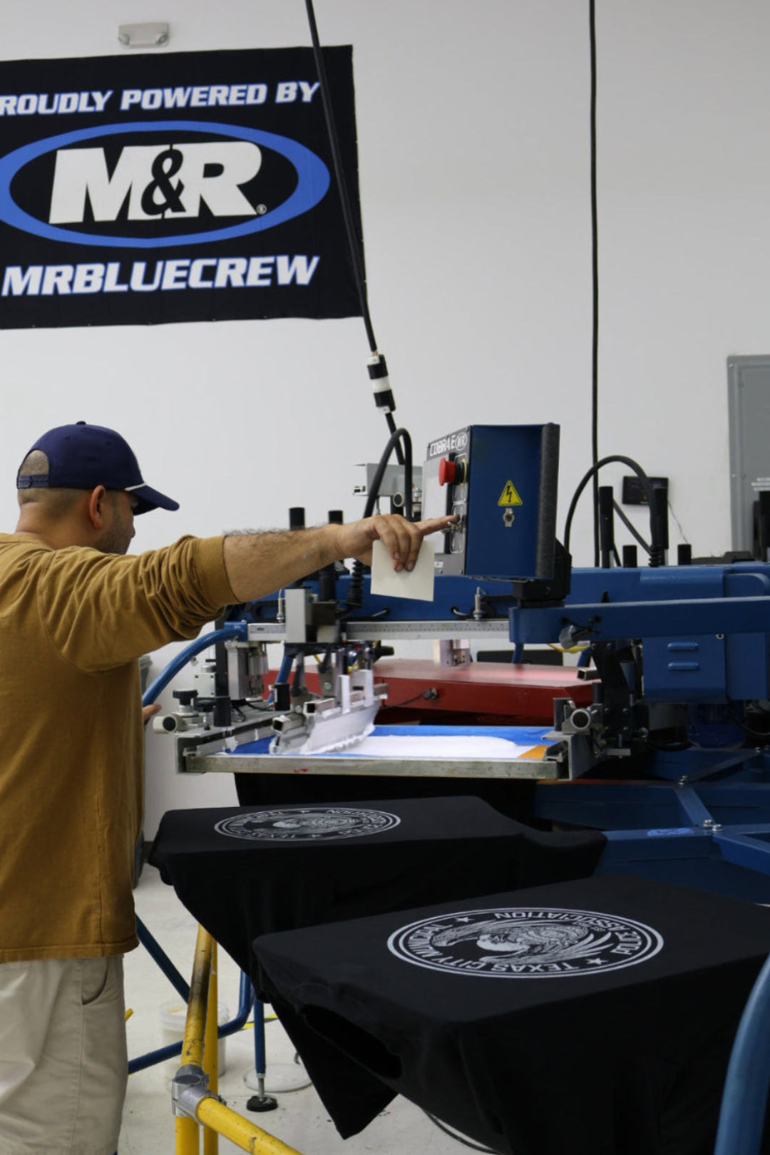 Person operating a machine with 'M&R' branding in the background