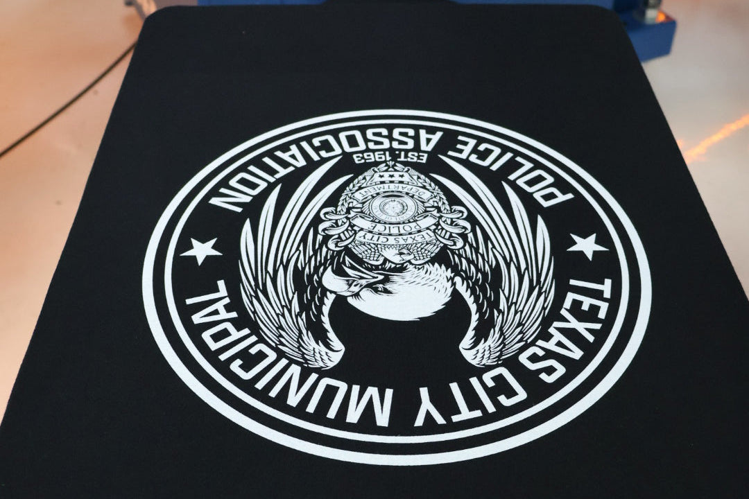 Black shirt with a white logo on a blue machine background